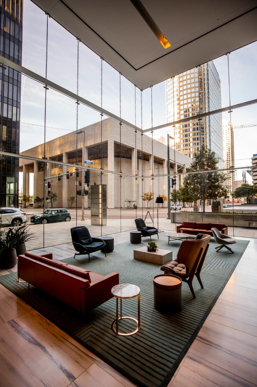 A modern hotel lobby with glass walls and lounge seating