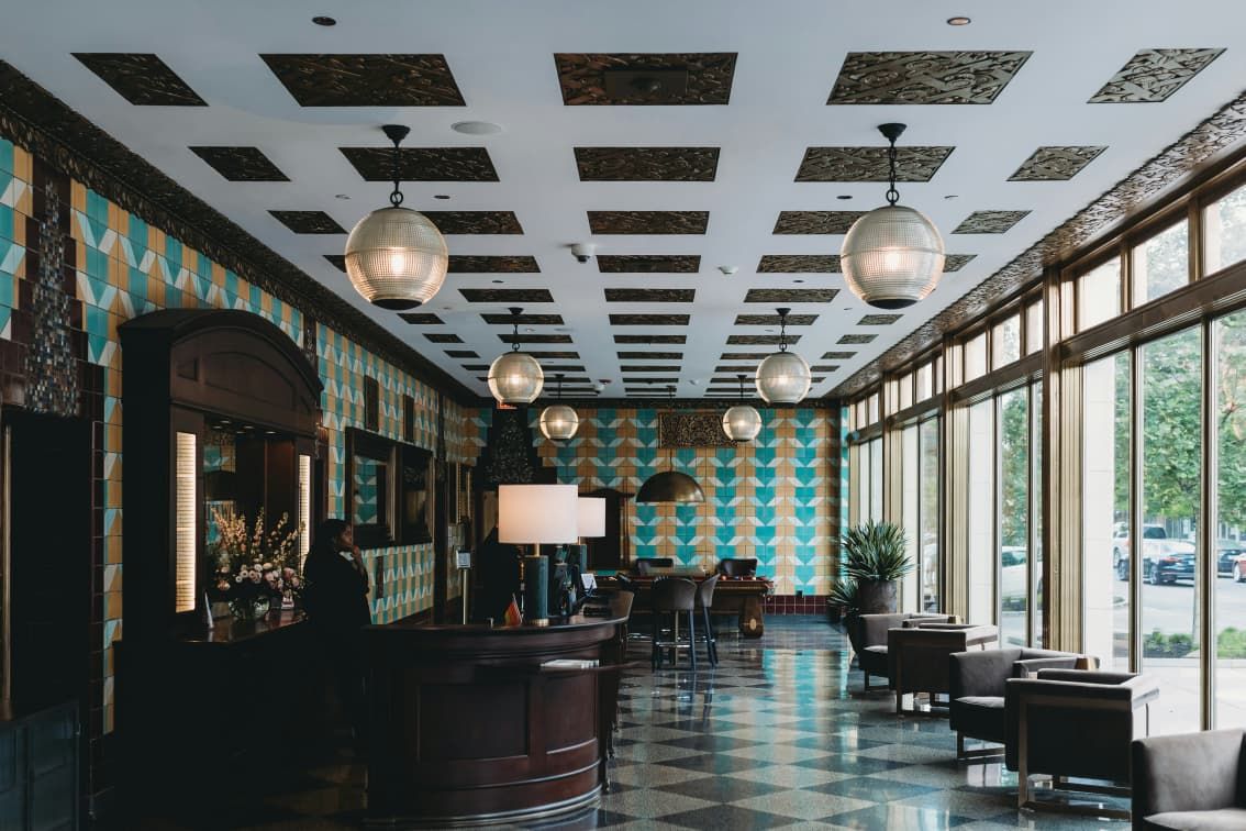 A hotel lobby with tiled walls and round pendant lamps