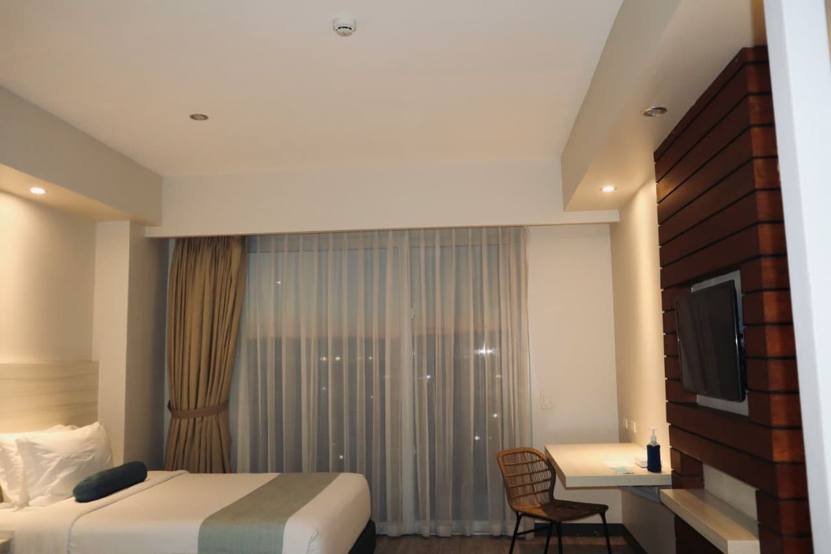 A hotel room with a bed, curtains and a work desk